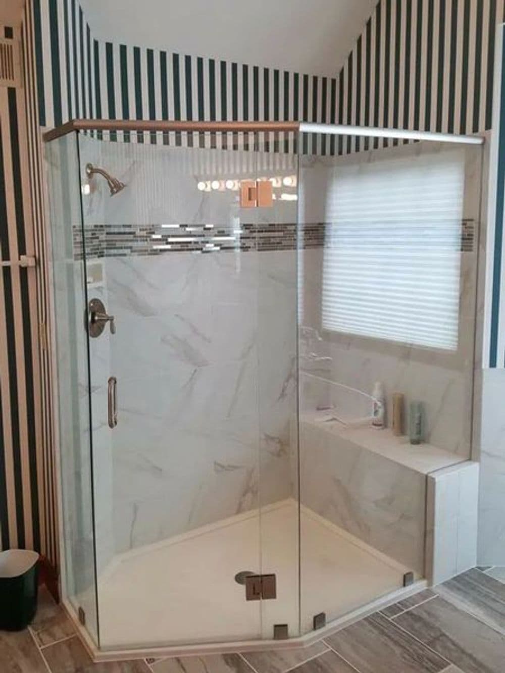 Modern glass shower enclosure with decorative tiles and a built-in bench in a stylish bathroom.