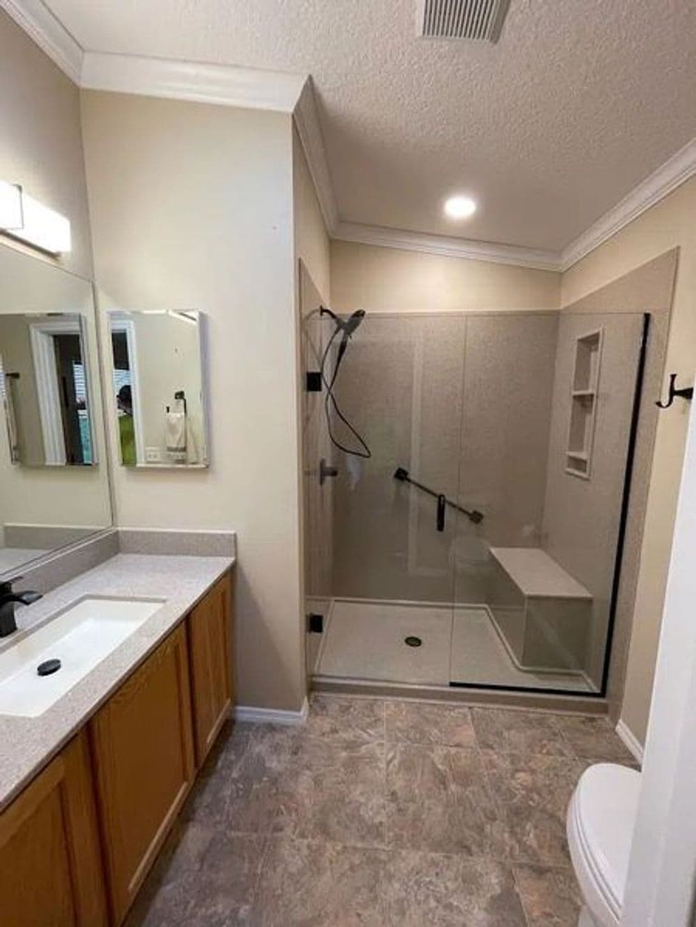 Bright, modern bathroom featuring a glass shower, vanity with sink, and decorative tiles.