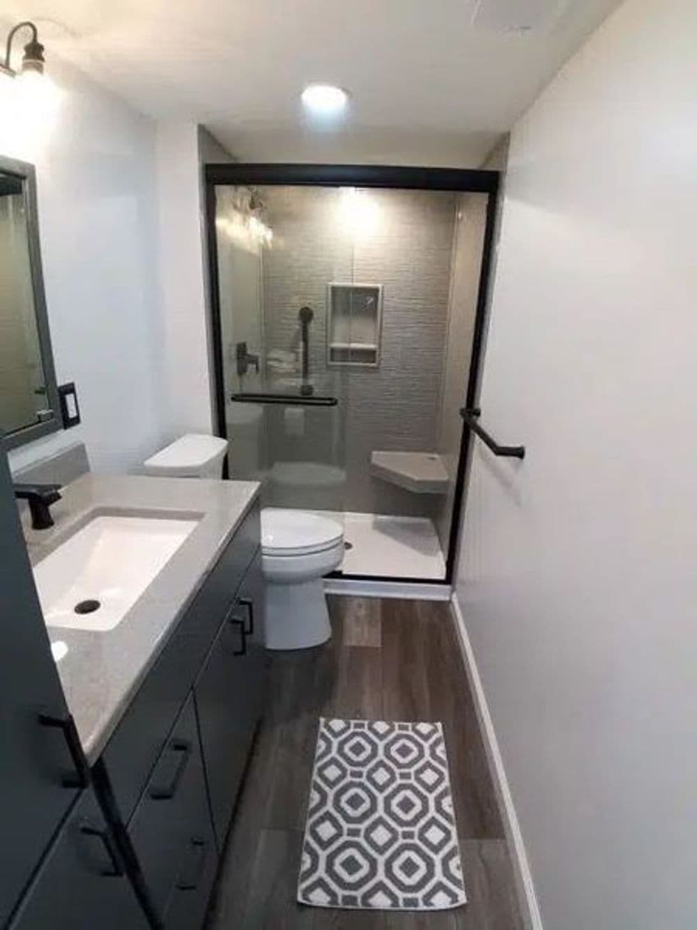 Modern bathroom featuring a glass shower, sleek vanity, and patterned rug.