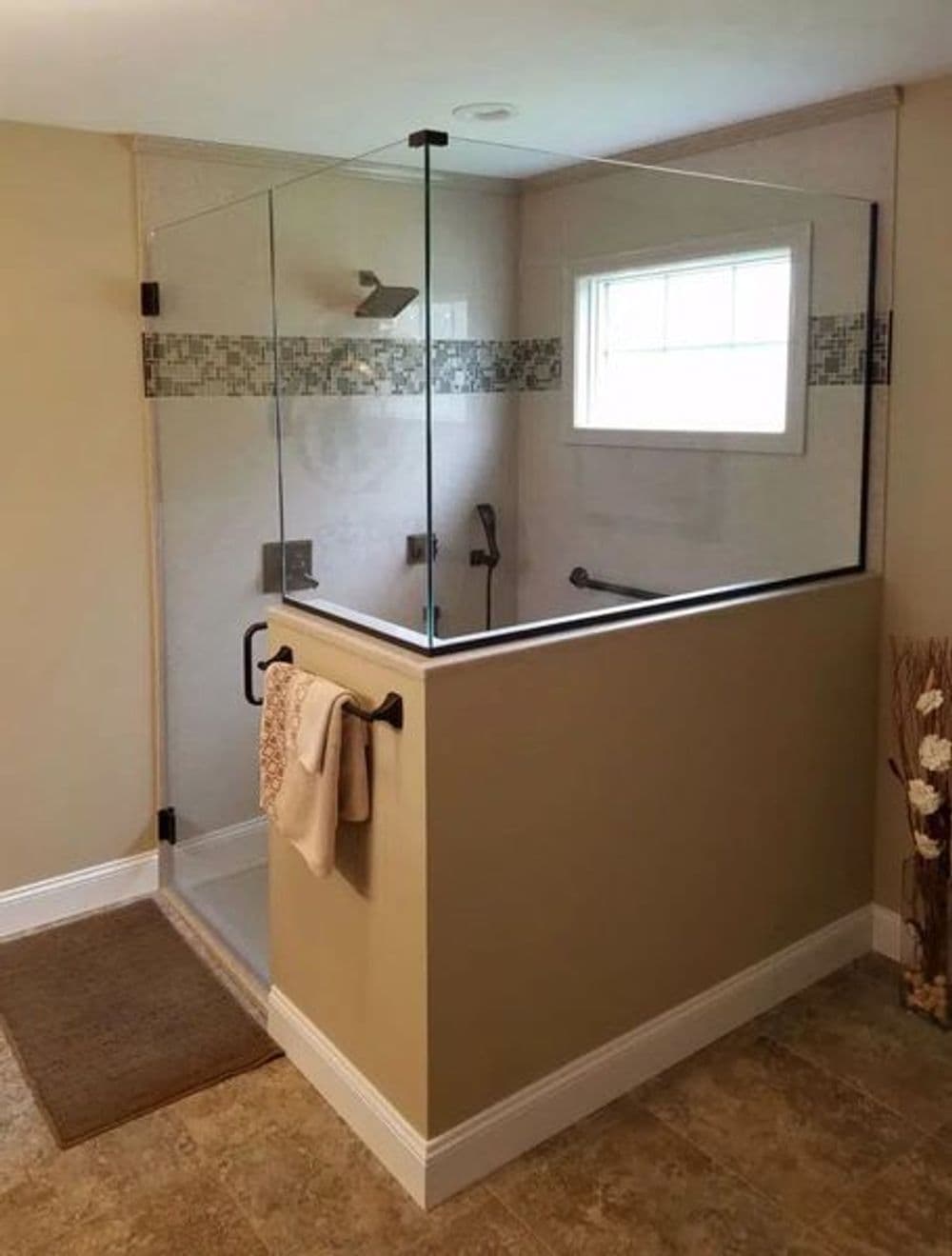 Modern glass shower enclosure in a neutral-toned bathroom with tile accents.