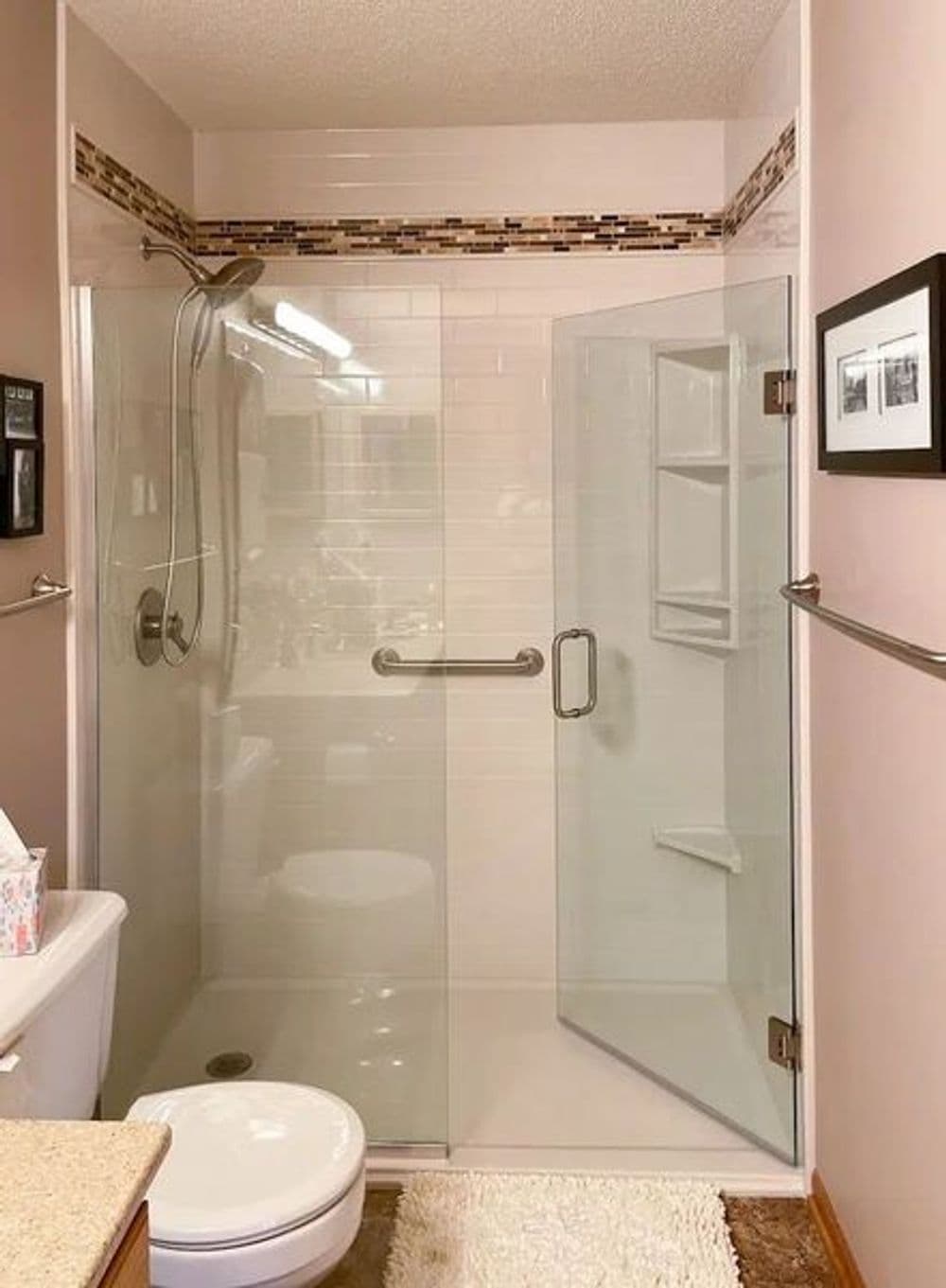 Modern bathroom with glass shower enclosure, beige walls, and stylish decor.