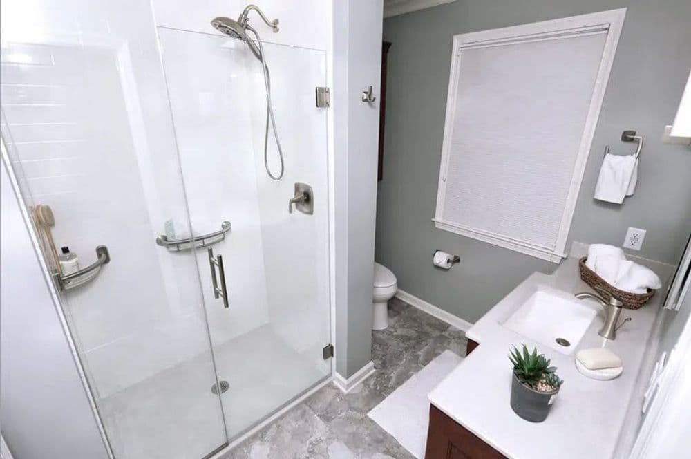 Modern bathroom featuring a glass shower, white vanity, and neutral color scheme.