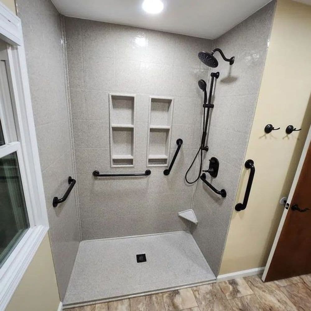 Accessible modern shower with grab bars, built-in shelves, and natural light.
