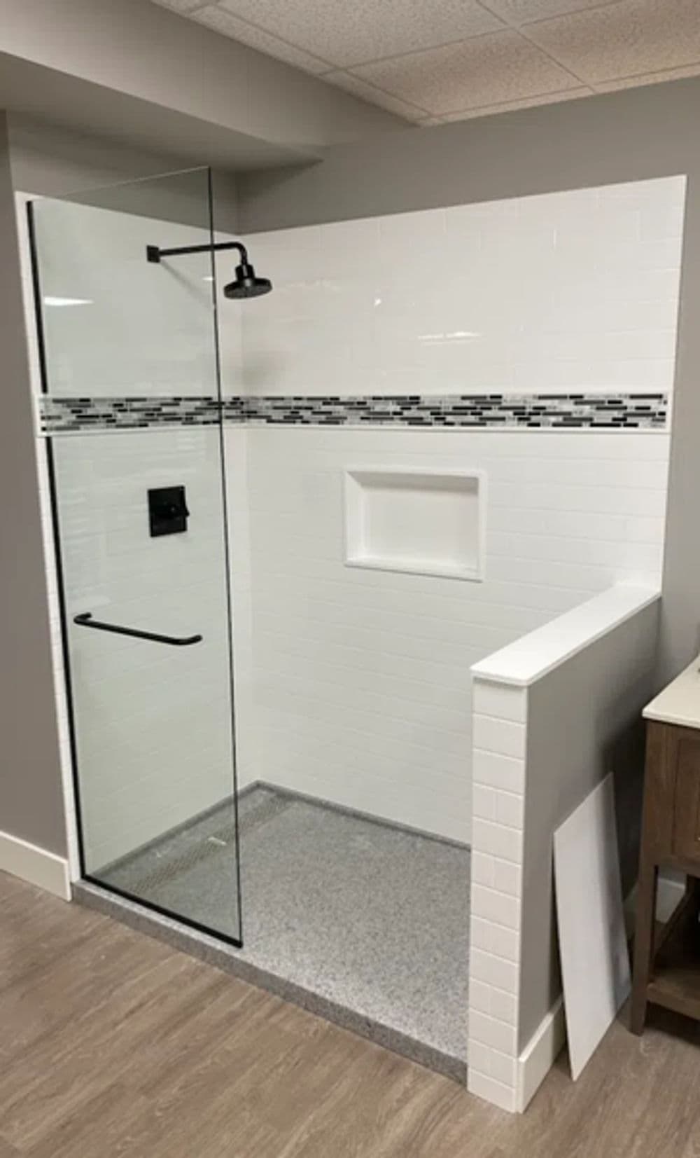 Modern shower design with glass door, tile accents, and built-in shelf in contemporary bathroom.