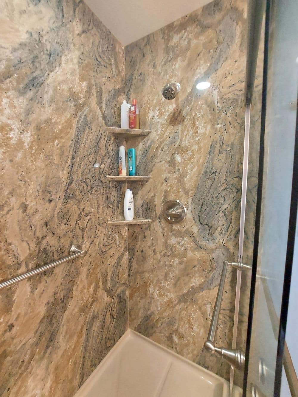 Modern shower with marble walls, built-in shelves, and sleek fixtures for storage.
